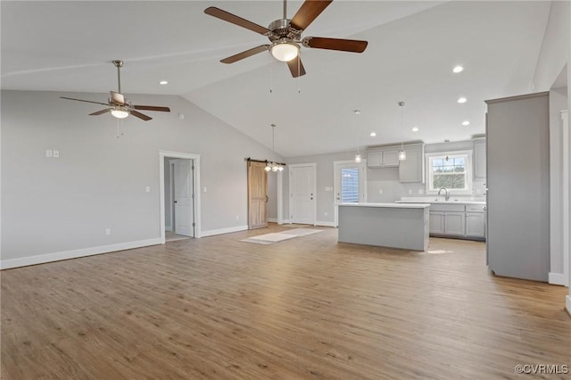 unfurnished living room with sink, high vaulted ceiling, ceiling fan, and light wood-type flooring