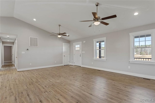 unfurnished living room with vaulted ceiling, a wealth of natural light, and light hardwood / wood-style flooring