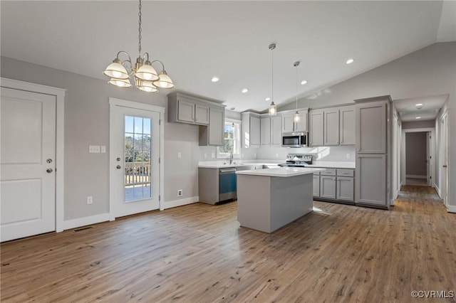 kitchen with stainless steel appliances, decorative light fixtures, a center island, and gray cabinetry