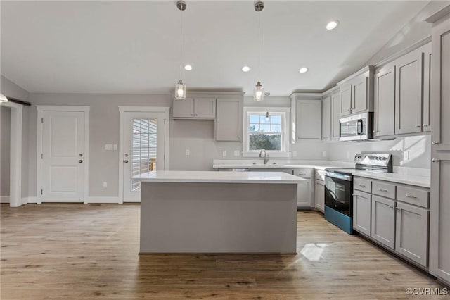 kitchen with sink, a center island, gray cabinets, pendant lighting, and stainless steel appliances