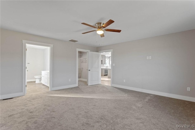 unfurnished bedroom featuring ensuite bath, ceiling fan, a spacious closet, light colored carpet, and a closet