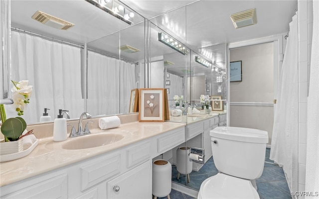 bathroom with toilet, vanity, and tile patterned floors