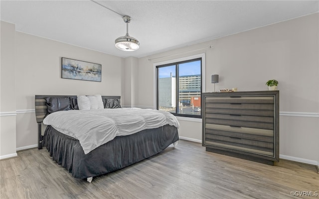 bedroom featuring a textured ceiling and light hardwood / wood-style flooring