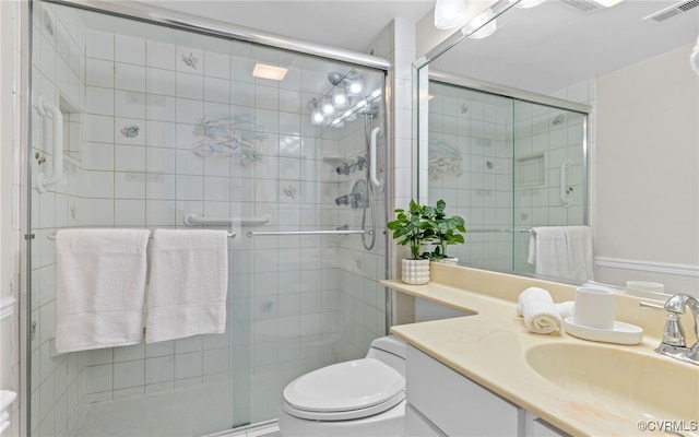 bathroom with a shower with shower door, vanity, and toilet