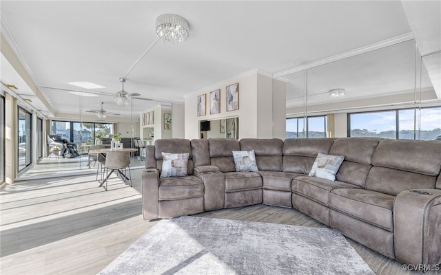 living room with ceiling fan with notable chandelier, crown molding, and hardwood / wood-style floors