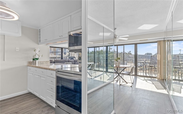 kitchen with white cabinetry, crown molding, ceiling fan, a textured ceiling, and light hardwood / wood-style flooring