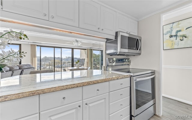 kitchen featuring light stone counters, stainless steel appliances, white cabinets, and light hardwood / wood-style flooring