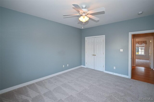 unfurnished bedroom featuring ceiling fan, a closet, and light carpet