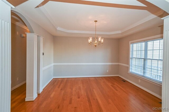 spare room with a raised ceiling, ornamental molding, light hardwood / wood-style flooring, and a chandelier