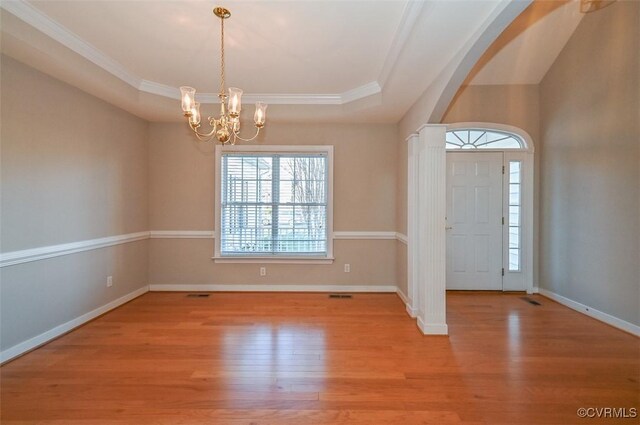 foyer featuring a raised ceiling, an inviting chandelier, and light hardwood / wood-style floors