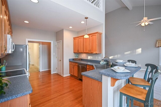 kitchen with sink, kitchen peninsula, a breakfast bar area, pendant lighting, and appliances with stainless steel finishes