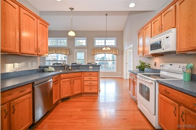 kitchen with white appliances, light hardwood / wood-style flooring, a chandelier, pendant lighting, and sink