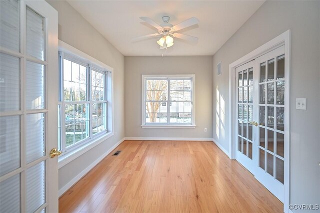 unfurnished sunroom featuring ceiling fan and french doors