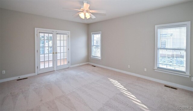 carpeted spare room with ceiling fan, french doors, and a wealth of natural light