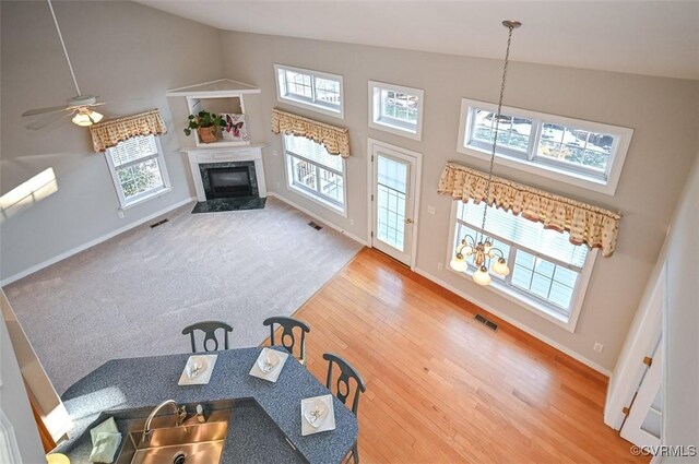 living room featuring ceiling fan with notable chandelier, a high end fireplace, and a healthy amount of sunlight