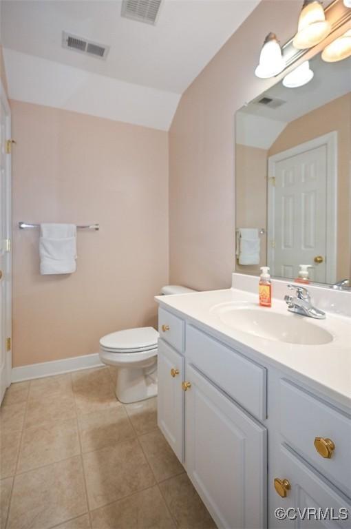 bathroom featuring toilet, vanity, tile patterned floors, and lofted ceiling