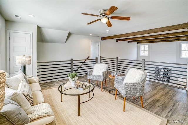 living area featuring ceiling fan, light wood-type flooring, and beam ceiling