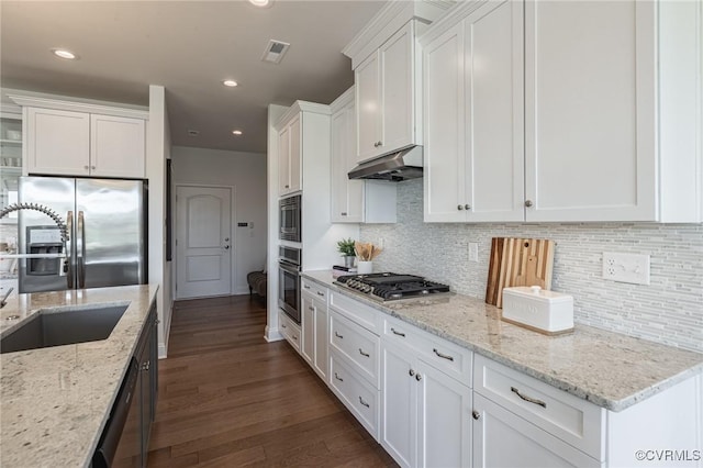 kitchen with appliances with stainless steel finishes, white cabinetry, sink, and light stone countertops