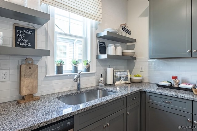 kitchen featuring sink, gray cabinetry, backsplash, and light stone countertops