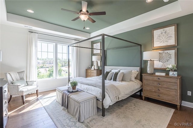 bedroom featuring wood-type flooring, ceiling fan, and a tray ceiling