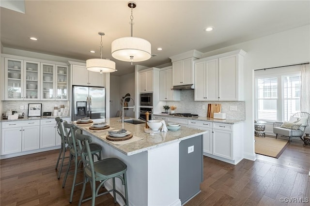 kitchen with stainless steel appliances, white cabinets, and an island with sink