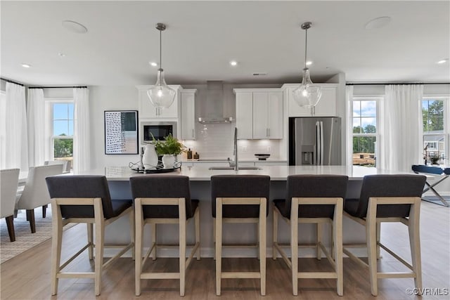 kitchen featuring stainless steel appliances, white cabinetry, tasteful backsplash, and wall chimney exhaust hood