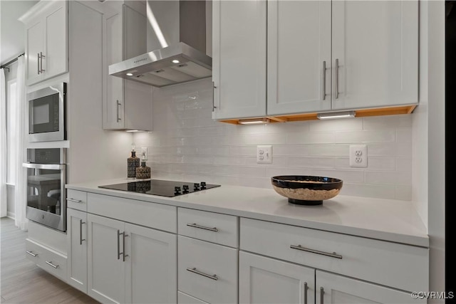 kitchen with stainless steel oven, white cabinetry, wall chimney exhaust hood, decorative backsplash, and black electric cooktop