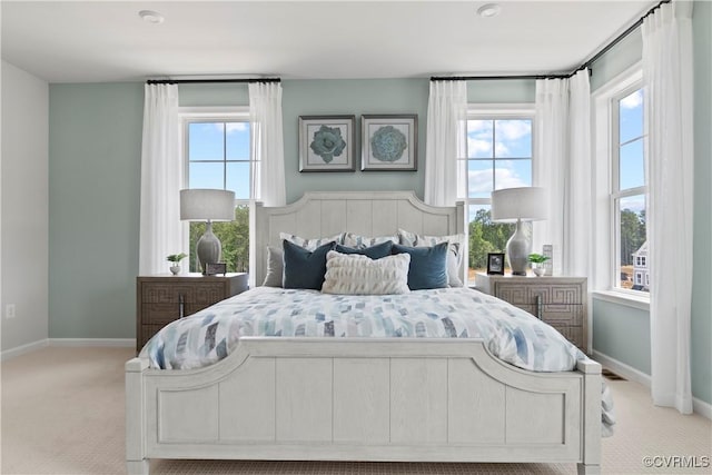 bedroom with light colored carpet and multiple windows