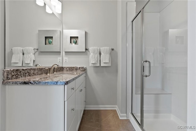 bathroom with a shower with door, vanity, and tile patterned floors