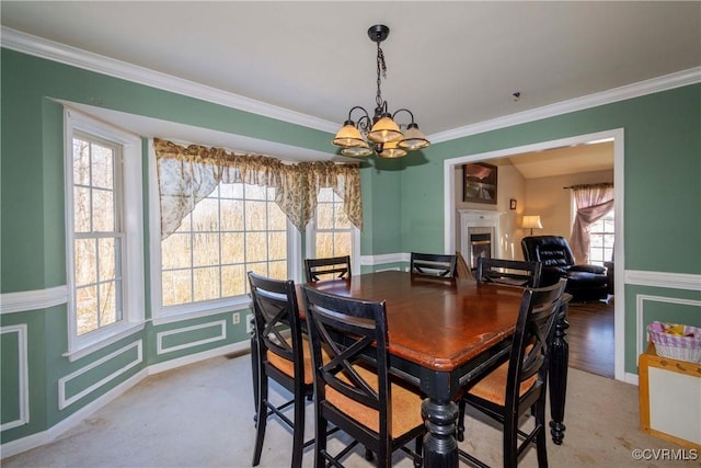 dining space with ornamental molding, a chandelier, and light carpet