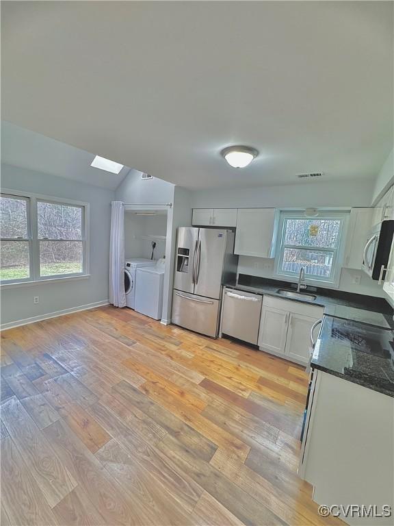 kitchen featuring light hardwood / wood-style flooring, stainless steel appliances, washing machine and dryer, white cabinets, and sink