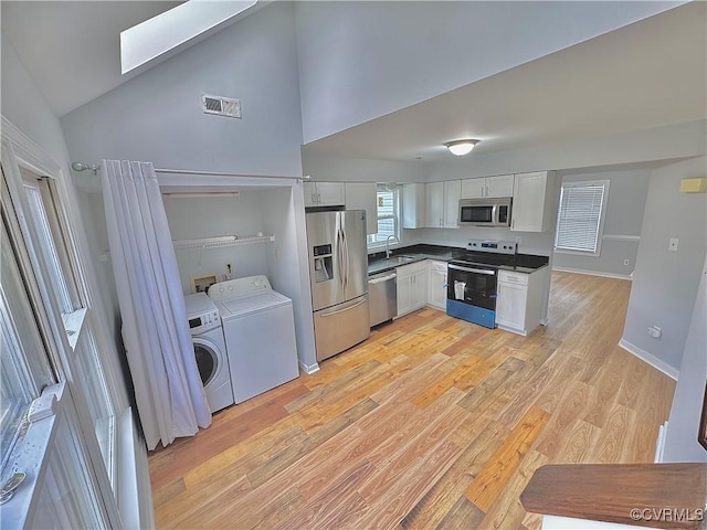 kitchen with sink, stainless steel appliances, washer and dryer, and white cabinetry