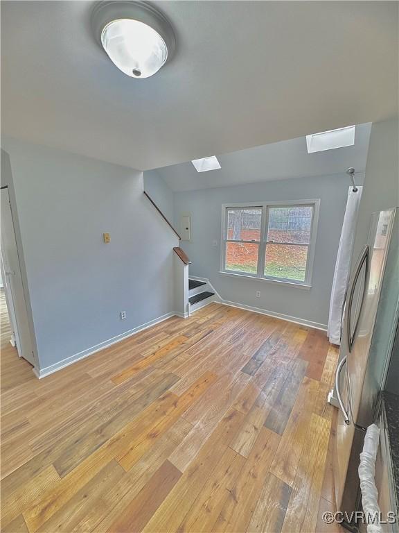 unfurnished living room with a skylight and light wood-type flooring