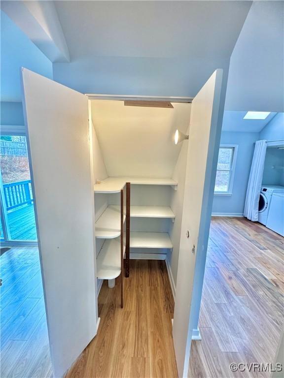 interior space featuring washer and dryer, light wood-type flooring, and a skylight