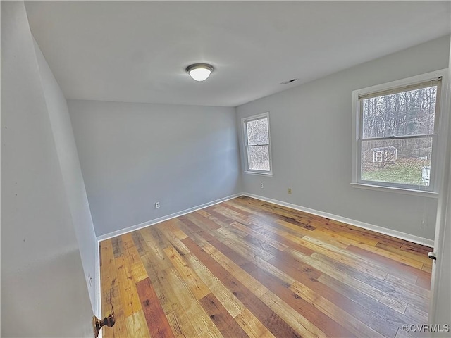 empty room with a wealth of natural light and hardwood / wood-style floors