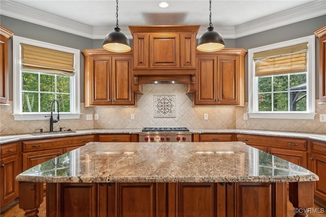 kitchen with a kitchen island, stainless steel gas stovetop, decorative light fixtures, and sink