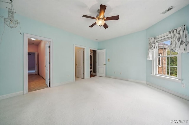 unfurnished bedroom with ensuite bath, light colored carpet, and ceiling fan