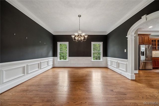 unfurnished dining area featuring a notable chandelier, hardwood / wood-style floors, crown molding, and a textured ceiling