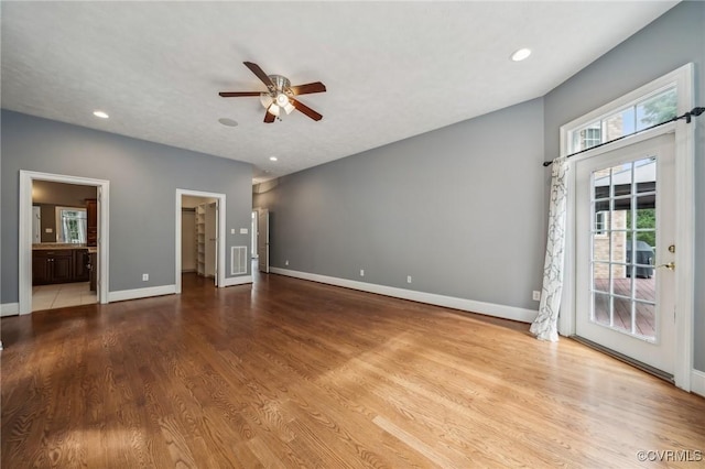 interior space featuring connected bathroom, light wood-type flooring, ceiling fan, a spacious closet, and access to outside