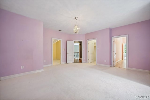 unfurnished bedroom with light colored carpet, ensuite bath, and a chandelier