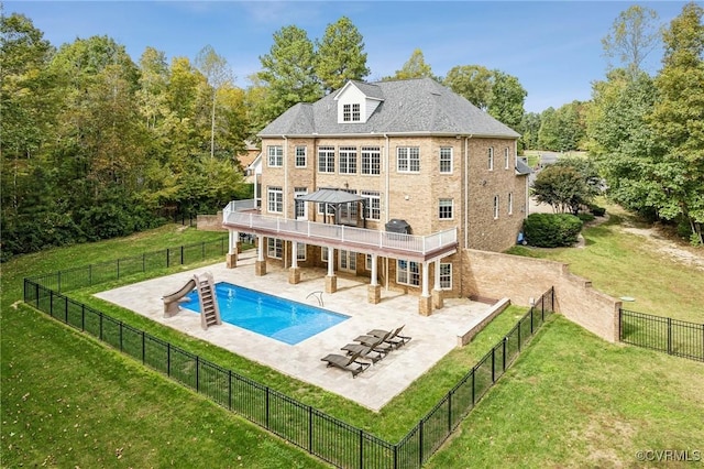 rear view of property with a lawn, a patio area, a balcony, and a fenced in pool