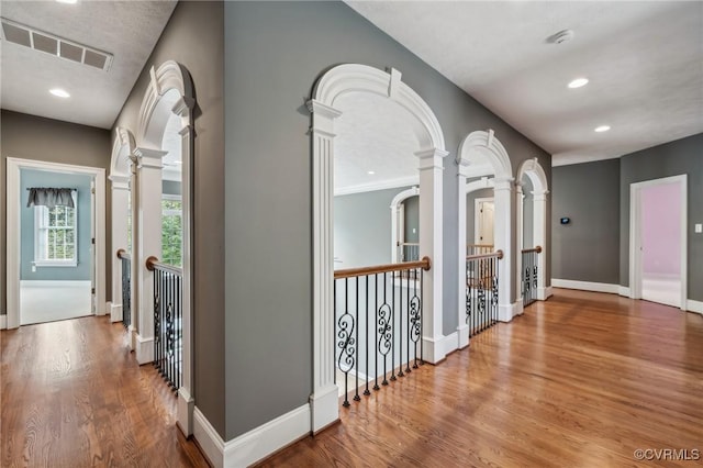 corridor with decorative columns and wood-type flooring