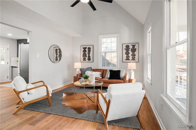 living room featuring a healthy amount of sunlight, ceiling fan, high vaulted ceiling, and wood-type flooring