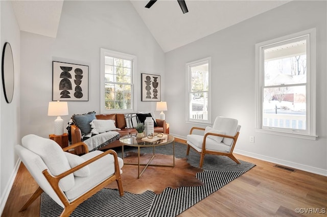 living area featuring high vaulted ceiling, ceiling fan, a healthy amount of sunlight, and light hardwood / wood-style flooring