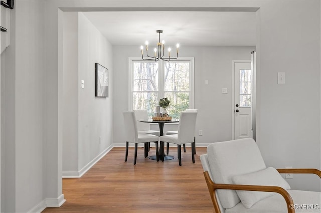 dining area with light wood-type flooring and a notable chandelier