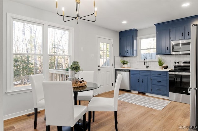 dining room featuring sink, light hardwood / wood-style floors, and a notable chandelier