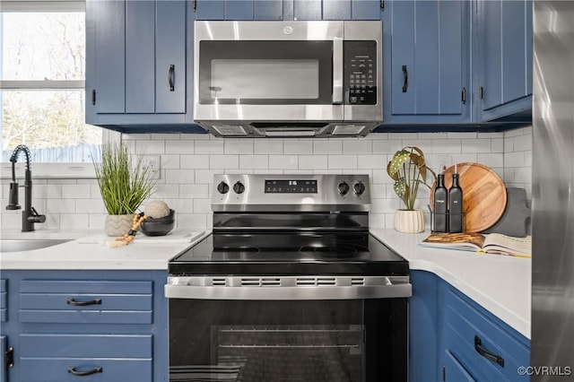 kitchen with blue cabinets, stainless steel appliances, sink, and decorative backsplash