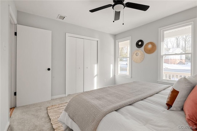 bedroom featuring ceiling fan, light colored carpet, a closet, and multiple windows