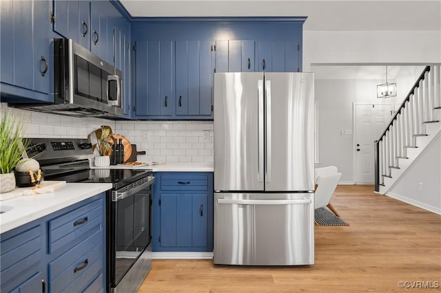 kitchen with decorative light fixtures, blue cabinetry, light hardwood / wood-style flooring, and appliances with stainless steel finishes