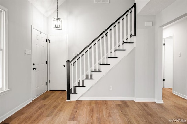 foyer entrance featuring lofted ceiling, a notable chandelier, and light hardwood / wood-style flooring